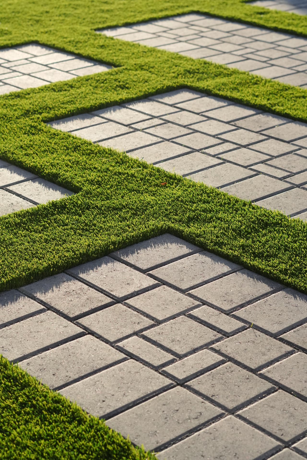 Close-up of artificial turf bands between grey paver squares