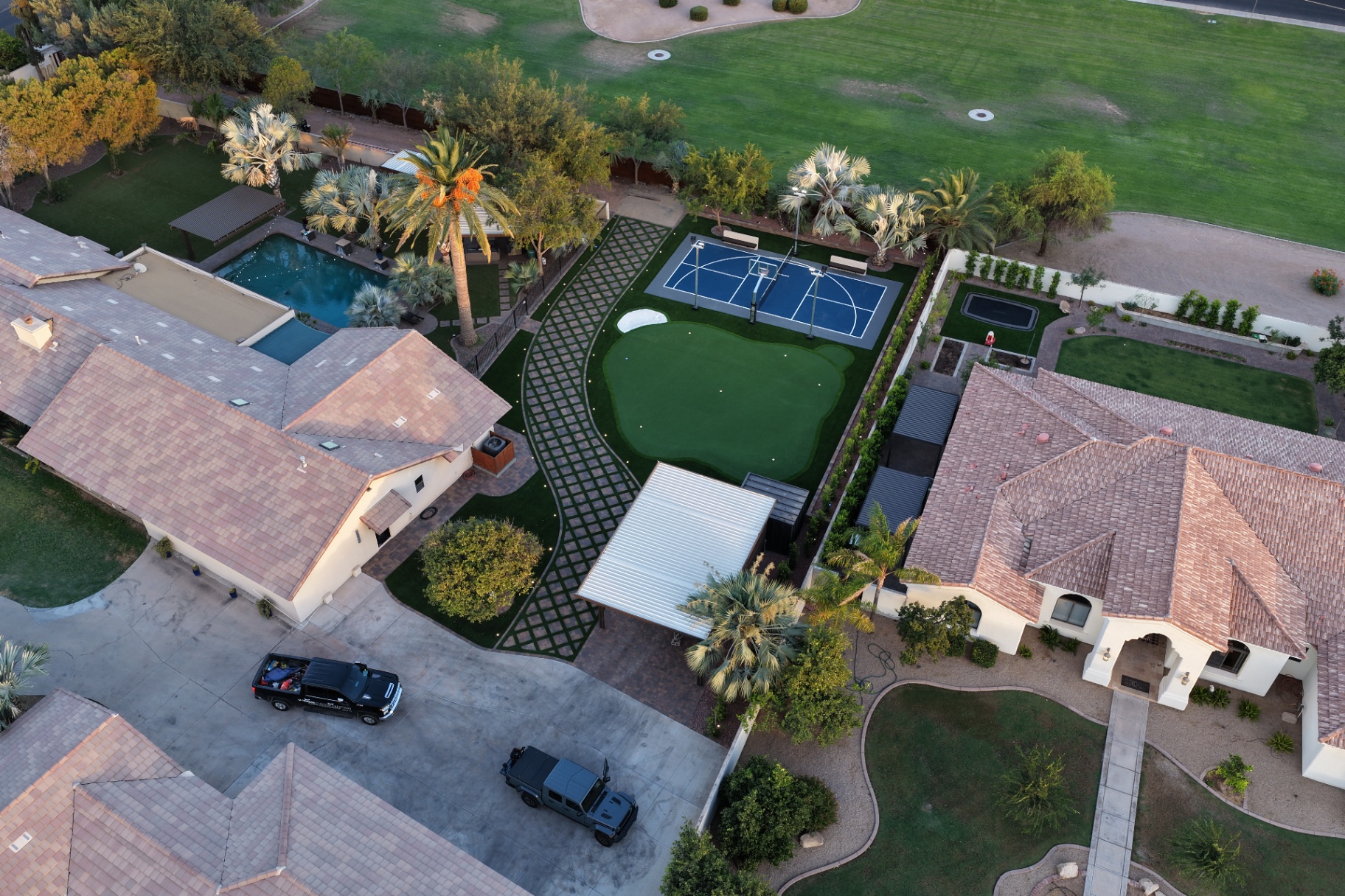 Aerial view of the estate showing pool, paver grid path, putting green and sport court