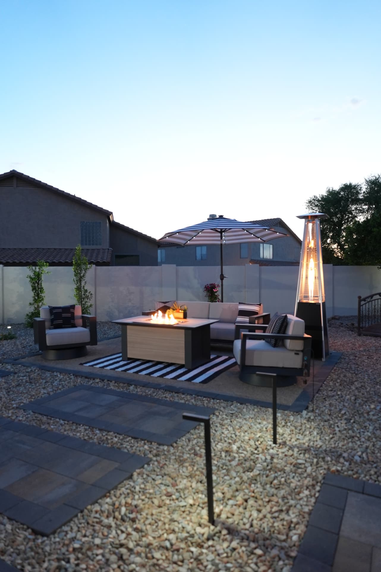 Outdoor fire table with lounge seating on gravel at dusk