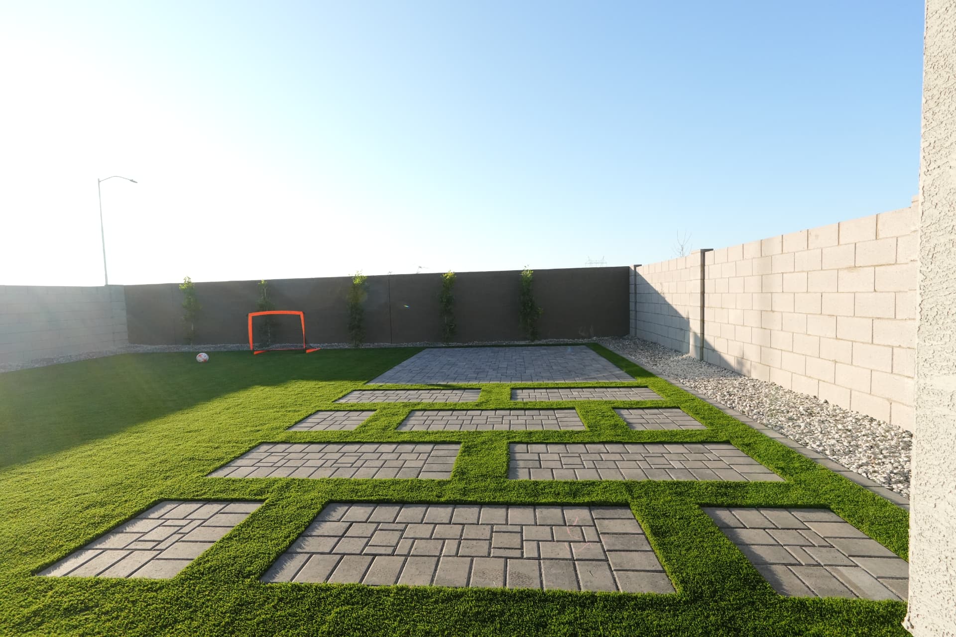 Paver and turf grid leading to a solid paver patio along a block wall