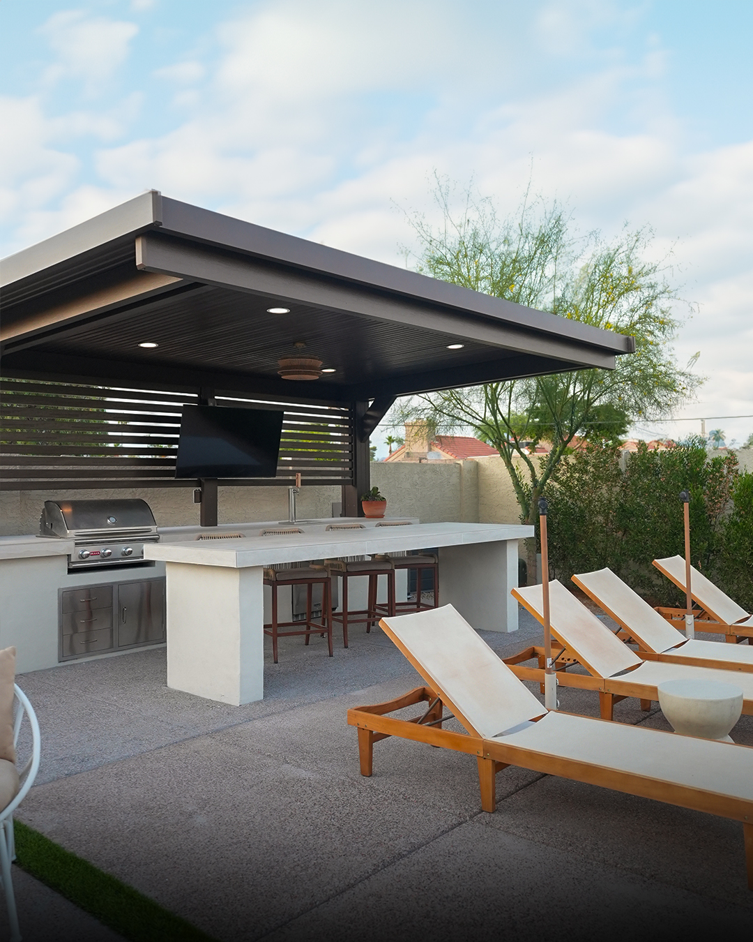 Outdoor kitchen island with bar stools under a cabana