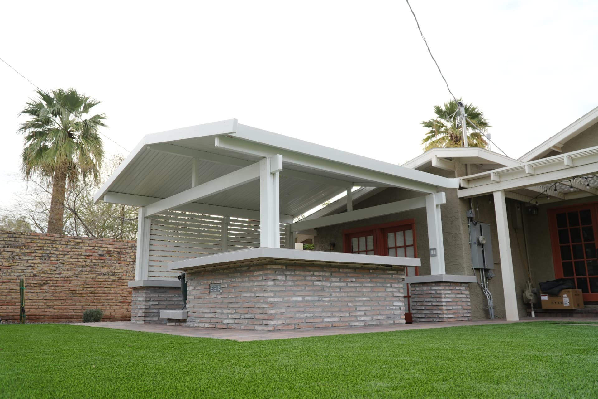 Angled view of the patio cover and raised brick bar counter beside the lawn