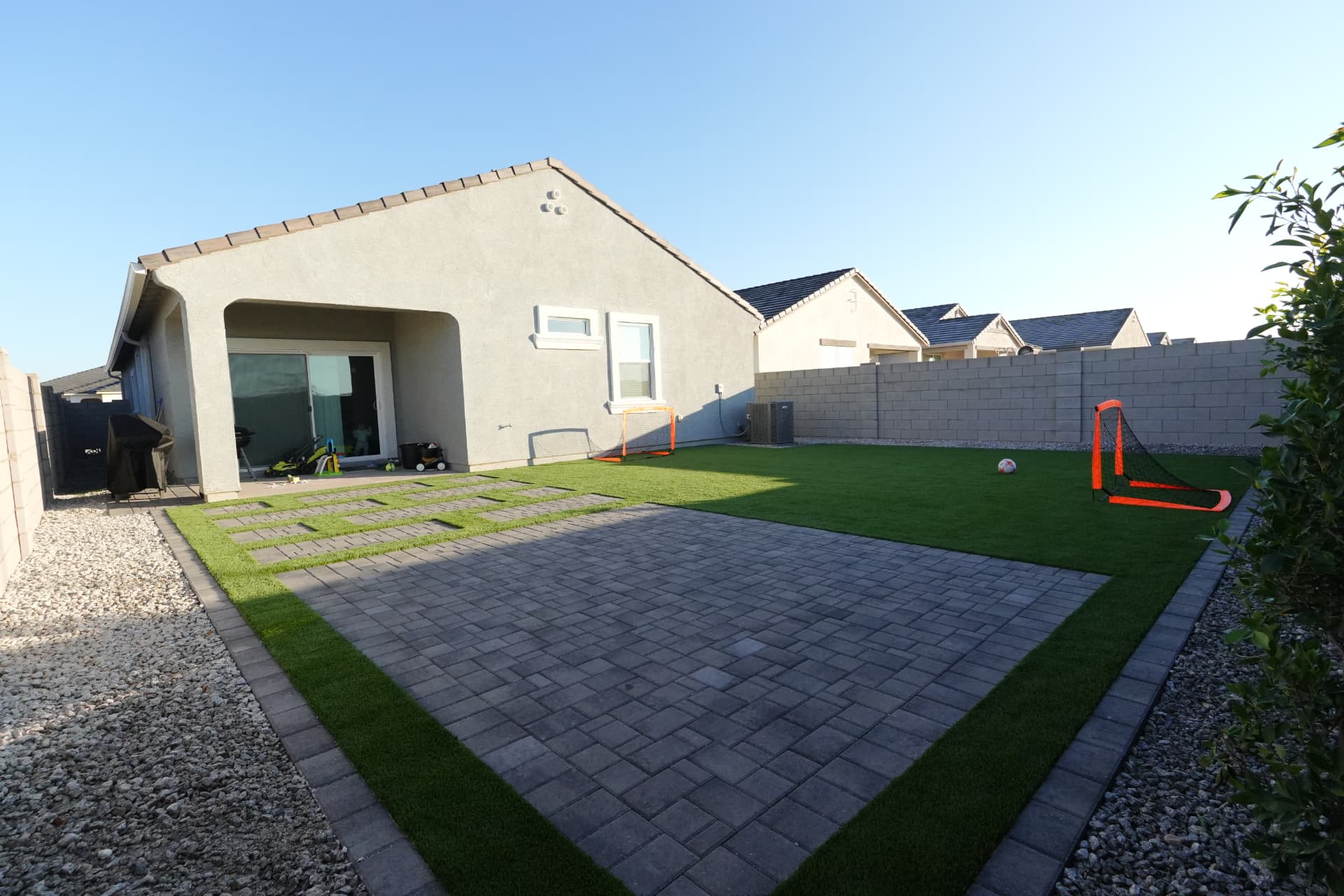 Large paver patio behind a single story home with turf borders