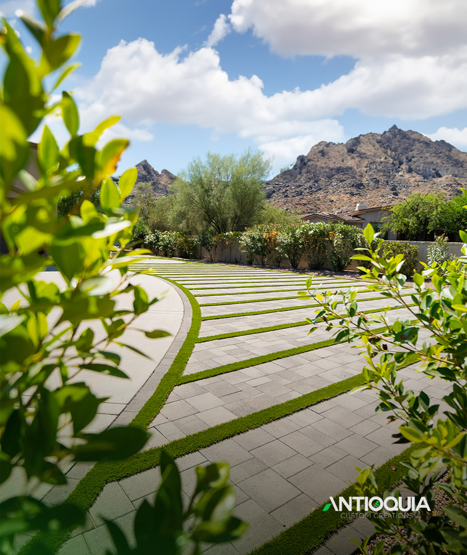 Turf ribbon paver court framed by green hedge foliage