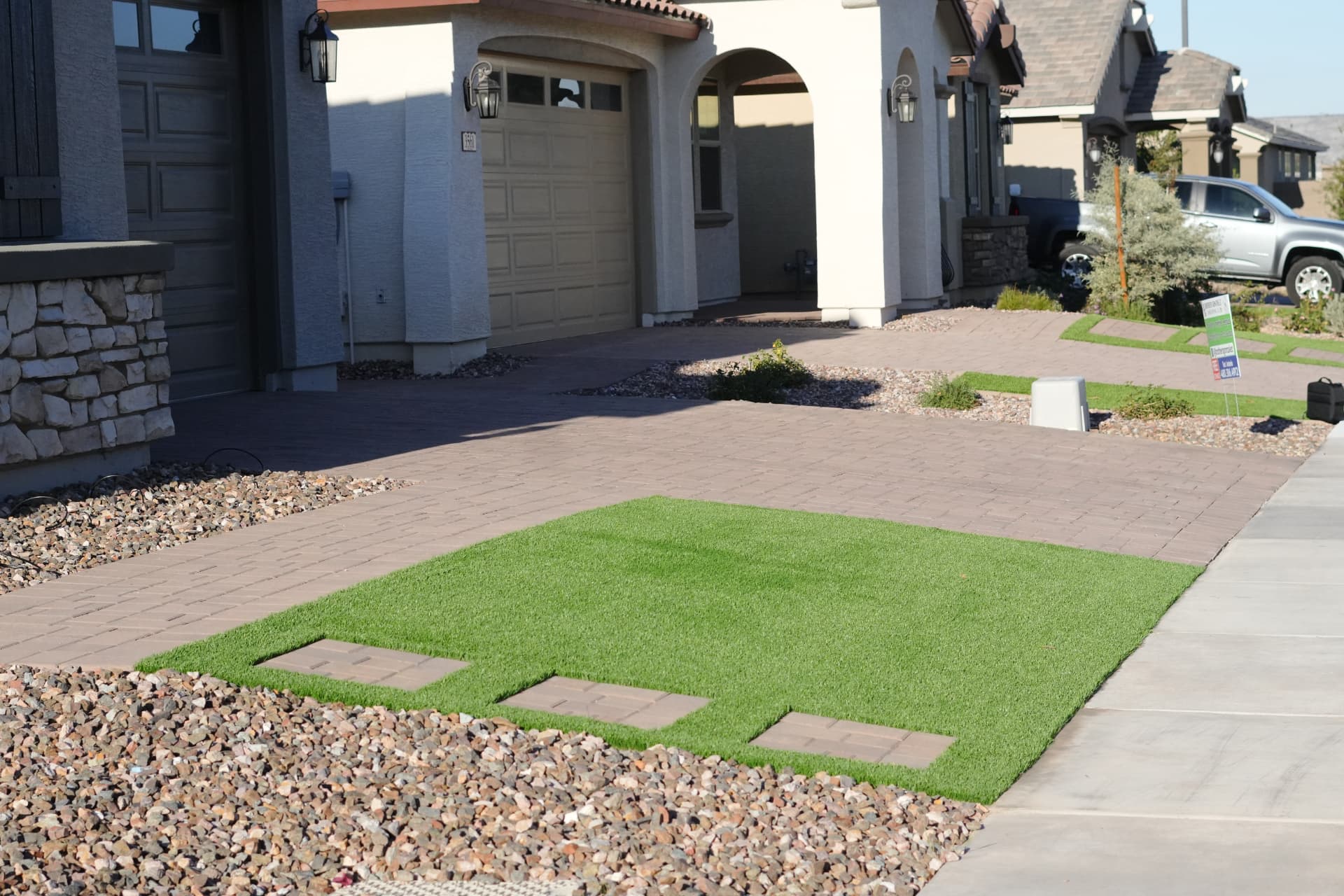 Front yard turf panel with inset paver stepping pads beside a paver driveway