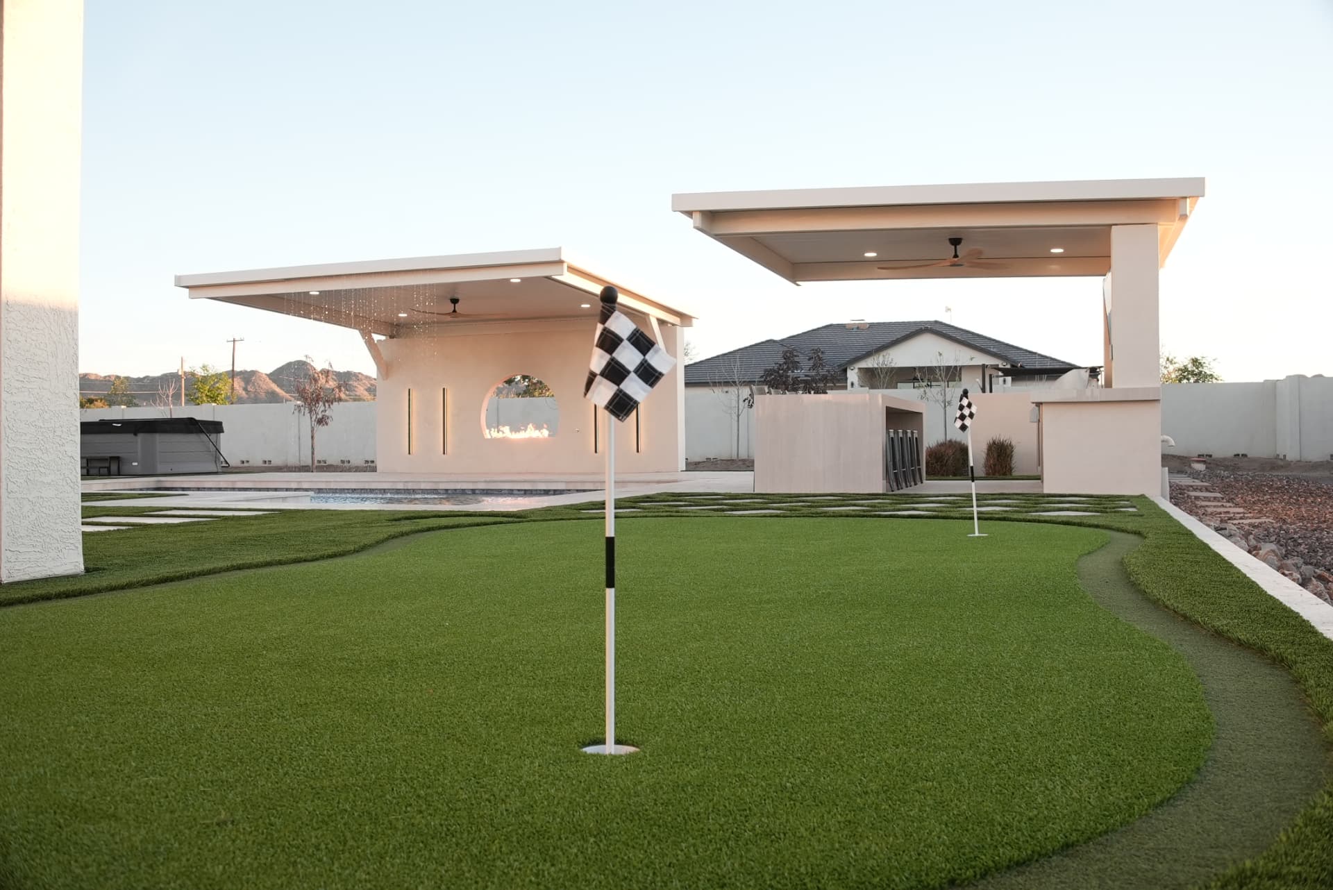 Backyard putting green with flags in front of two pavilions
