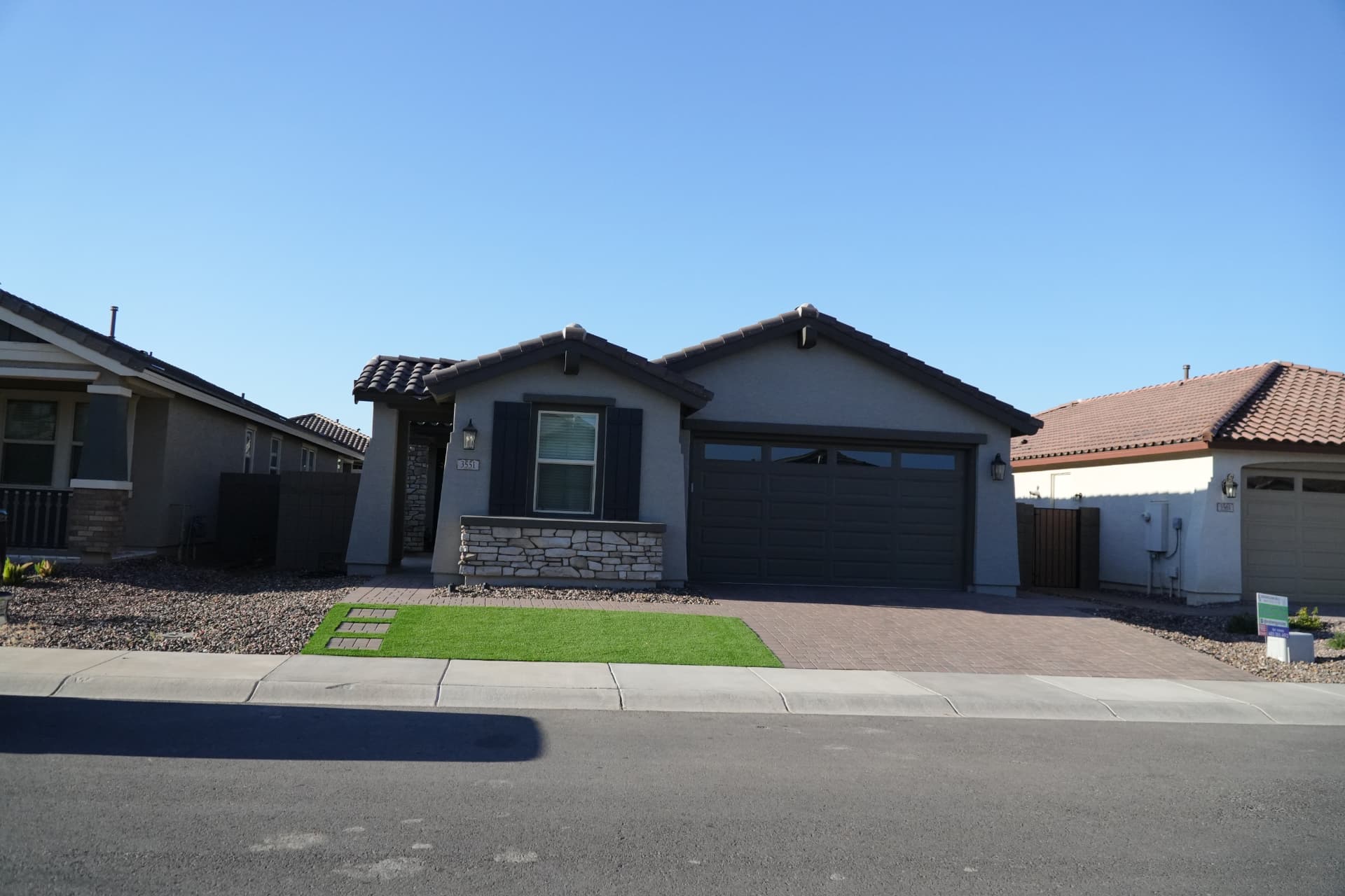 Street view of a Queen Creek home with a small turf lawn and paver driveway