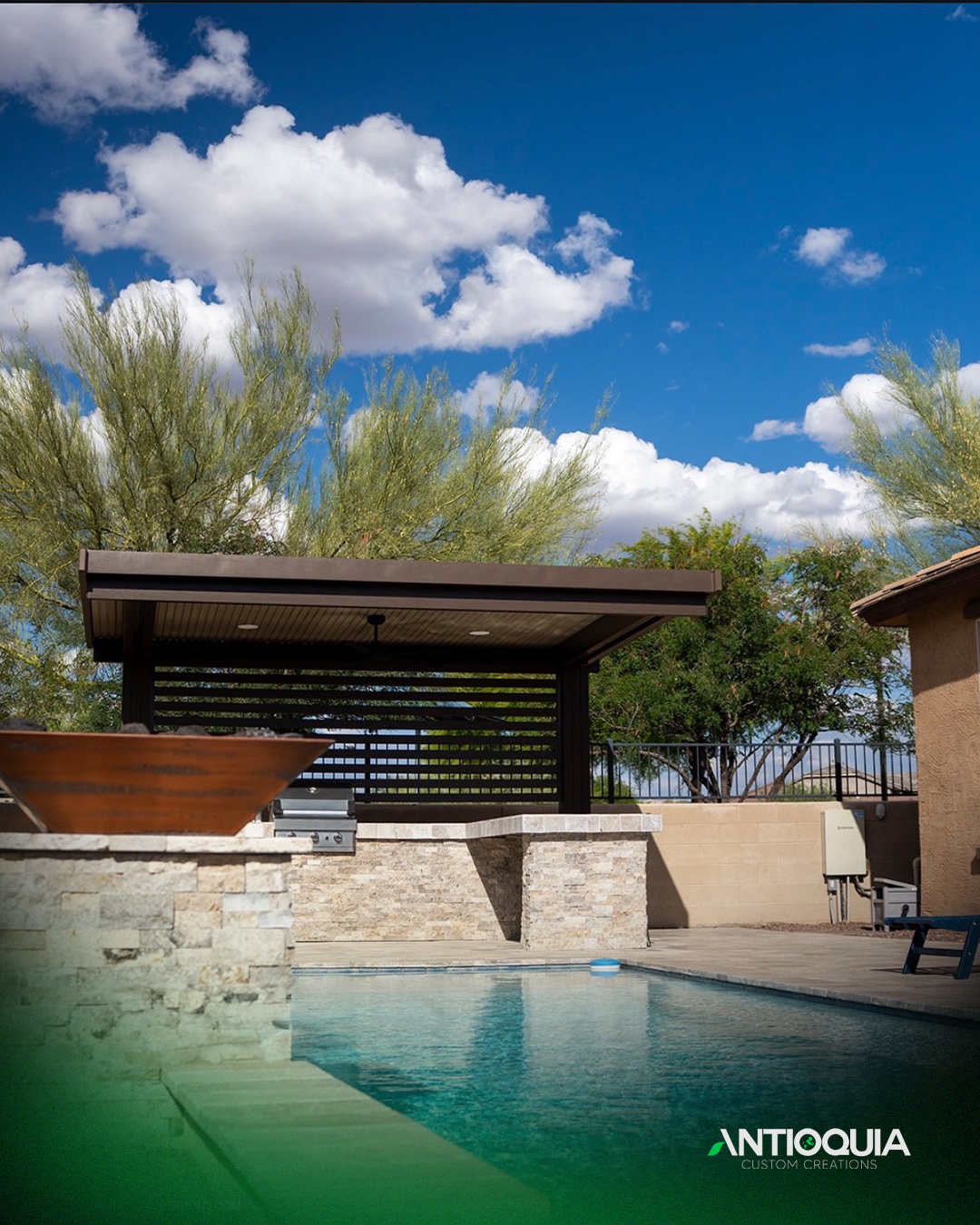 Pool and pavilion under a bright sky with travertine decking