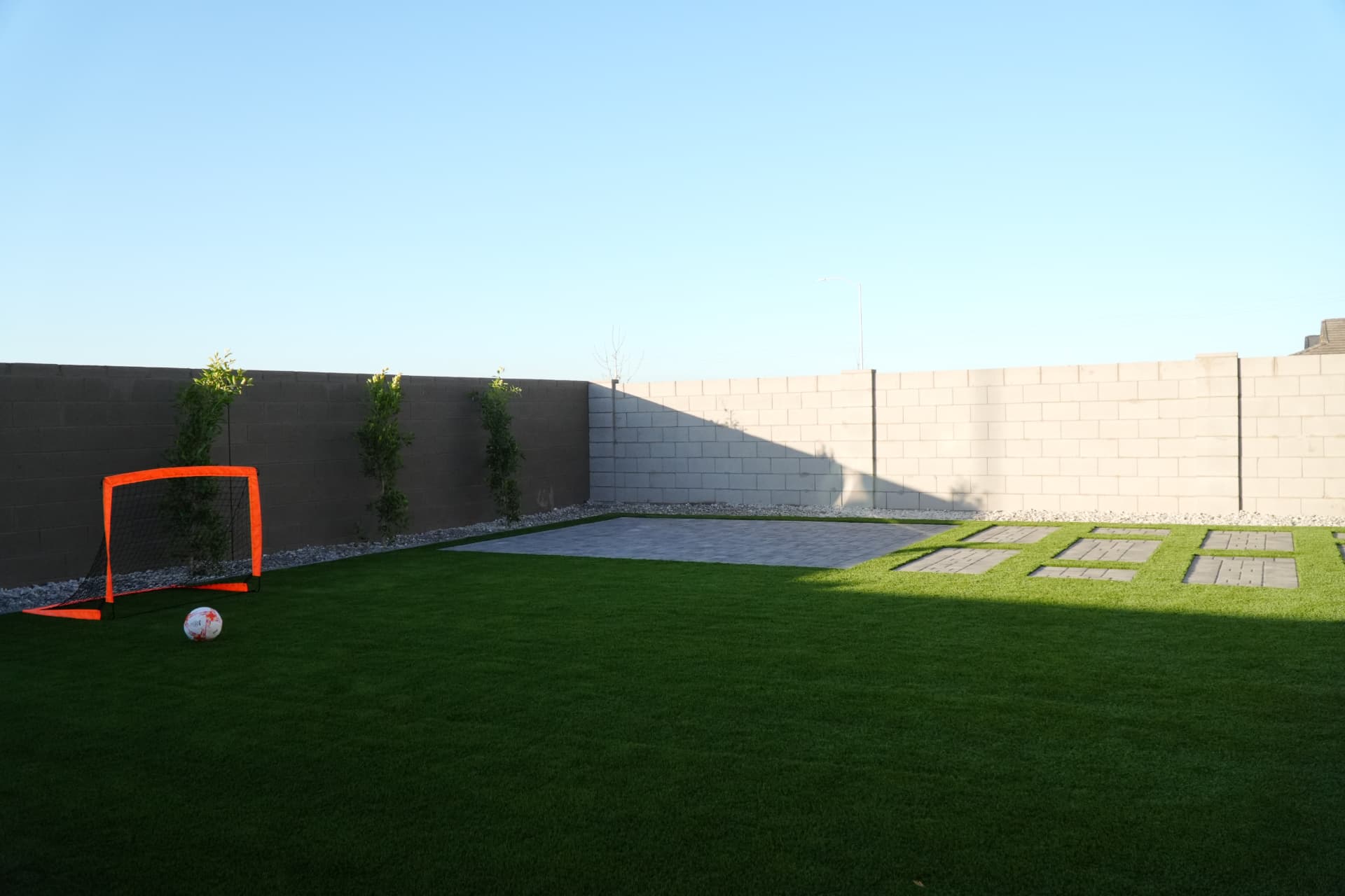 Artificial turf play lawn with a soccer goal against a block wall