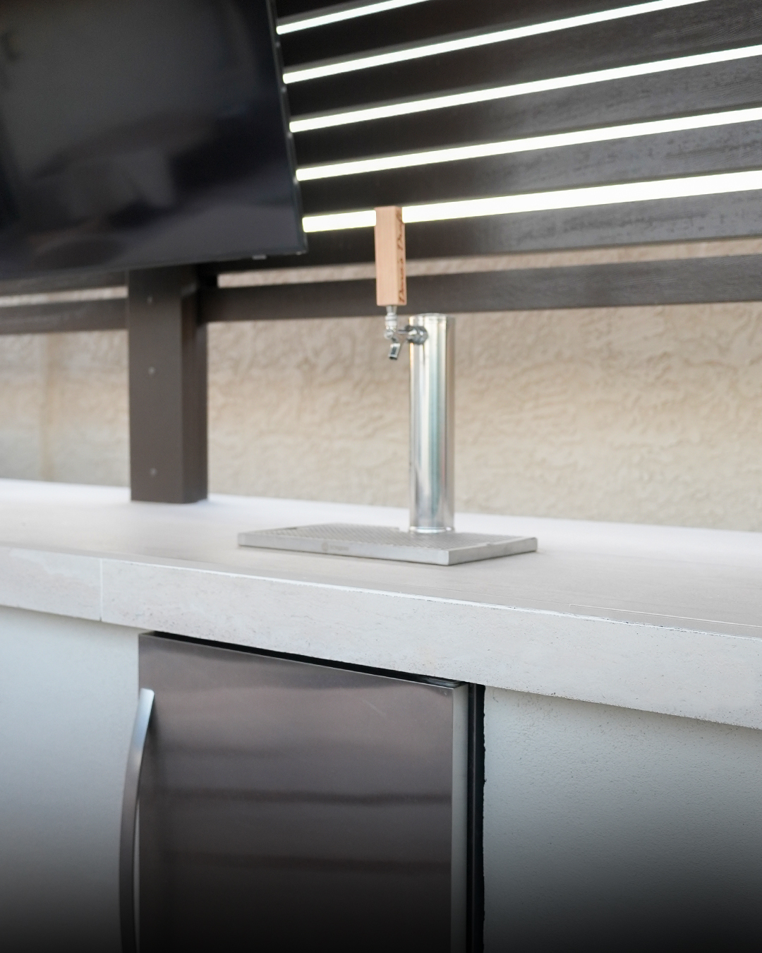Draft beer tap on an outdoor counter above a stainless fridge