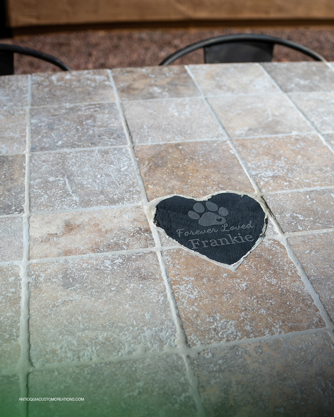 Engraved slate heart memorial stone set into a travertine tile bar top