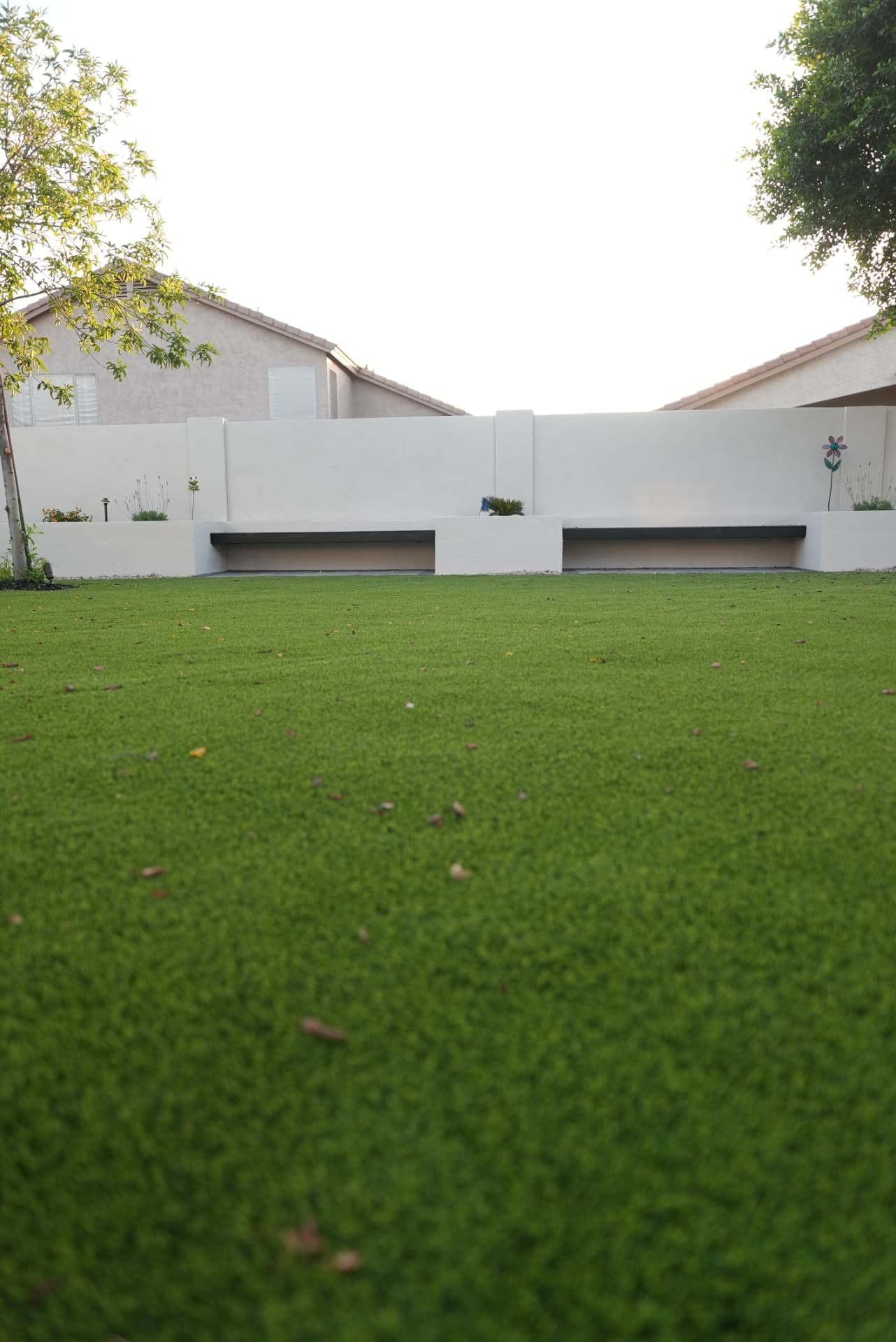 Artificial turf lawn in front of white stucco planters and bench seating