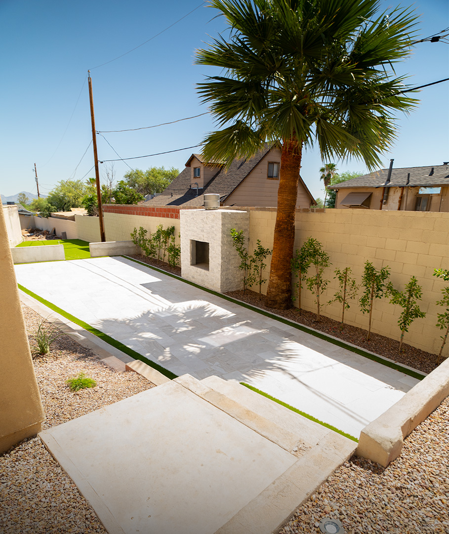 Travertine side yard patio with masonry fireplace and palm tree